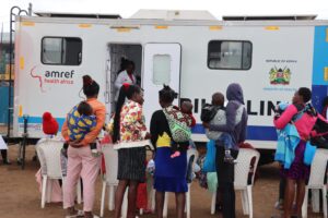 Mothers carrying their children while waiting to be treated at an AMREF mobile clinic.